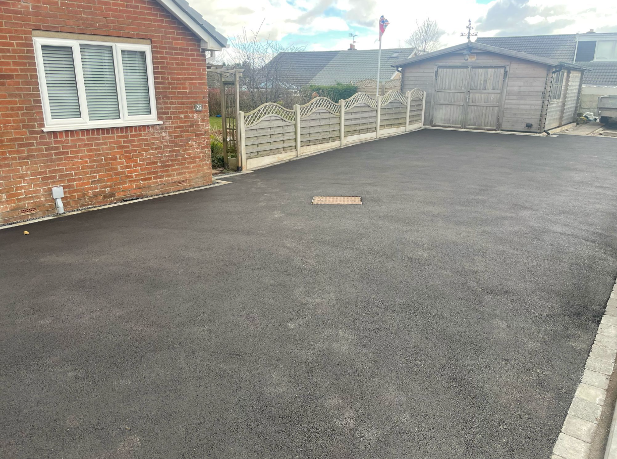 Large asphalt driveway leading to a garage