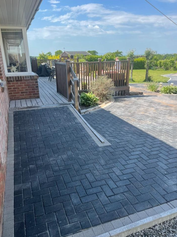 Dark block paved patio next to a wooden deck